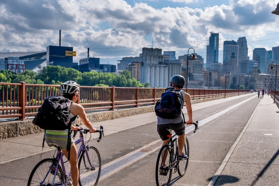 Two people on bikes riding toward downtown Minneapolis, Minnesota on Stone Arch Bridge.